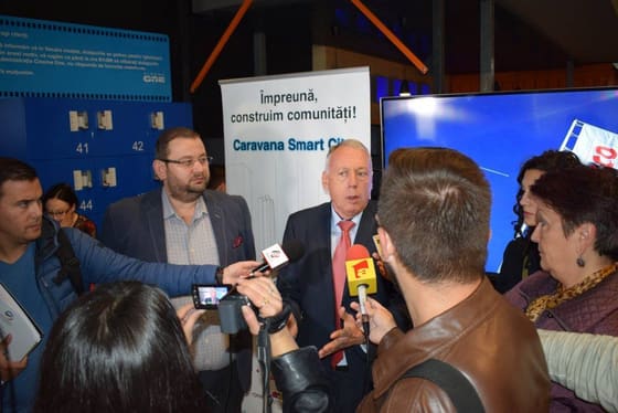 Vorbitor înconjurat de microfoane și camere de filmat.