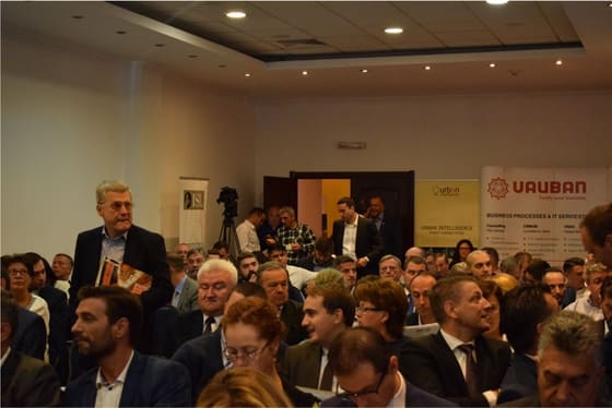 Sală plină văzută din spate, în timpul unei prezentări.