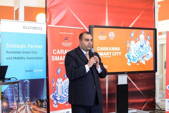 Vorbitor cu microfon, în fața unui banner Caravana Smart City.