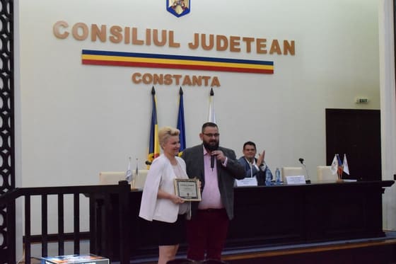 Vorbitoare la pupitru, în sala Consiliului Județean Constanța.