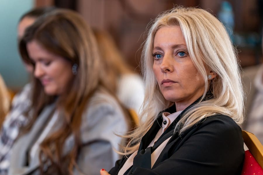 Participantă în public, urmărind atent discuția din sală.