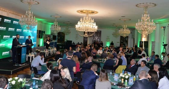Seară de gală cu mese rotunde și lumină verde.